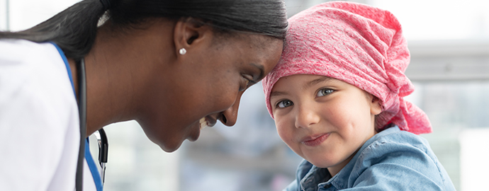girl with cancer is wearing a pink scarf on her head at a medical appointment. 
