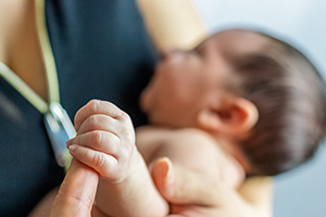 Baby holding finger of health-care provider